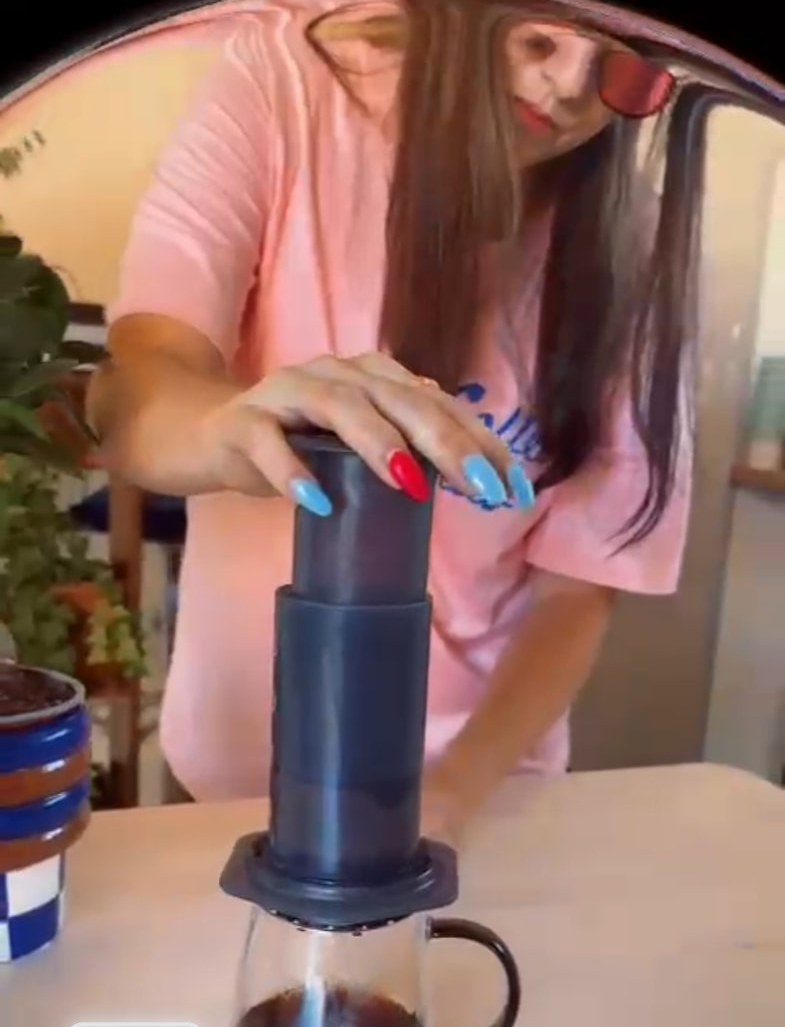 Hayley pressing an AeroPress into a glass mug of filter coffee at a brew bar